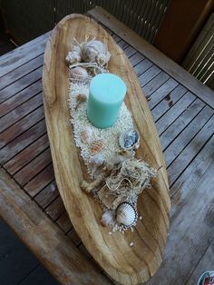 a wooden table topped with a candle and seashells on top of wood planks