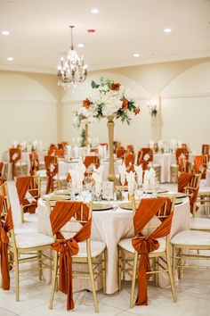 the tables are set up with white and orange linens for an elegant wedding reception