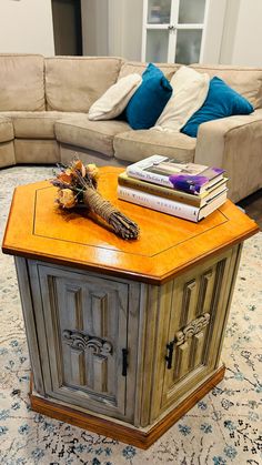 a living room with a couch, coffee table and books on top of the cabinet