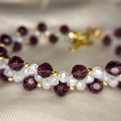 a close up of a bracelet with beads and crystals on white fabric background, focus on the bead