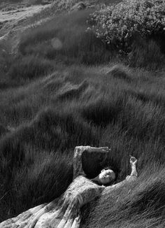 black and white photograph of a woman laying in the grass