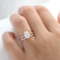 a woman's hand with a diamond ring on top of her finger and the other hand holding an engagement ring