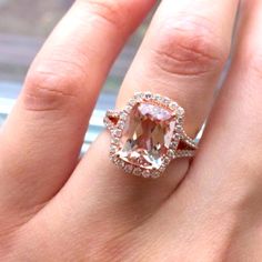 a woman's hand with an engagement ring on top of it and a pink diamond in the middle