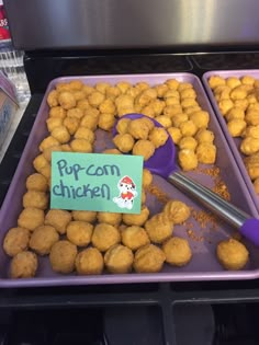 two trays filled with different types of food and one has a sign that says popcorn chicken