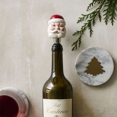 a bottle of wine with a santa clause on it next to a plate and tree decoration