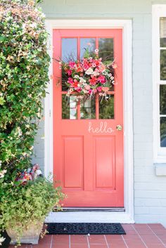 a bright pink door with the word hello written on it and flowers in front of it