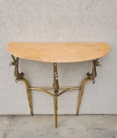 a wooden table sitting on top of a cement floor next to a white stucco wall