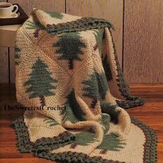 a crocheted blanket is sitting on the floor next to a cup and mug