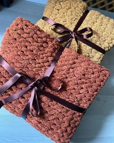 three crocheted blankets tied together with brown ribbon on top of each other,