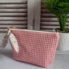 a pink purse sitting on top of a table next to a potted plant