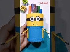 a hand holding a pencil holder made out of construction paper