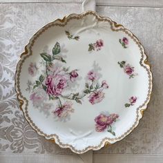 a white and gold plate with pink flowers on it