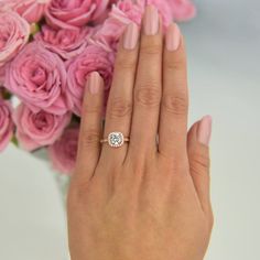 a woman's hand with pink roses and a diamond ring