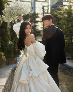 a young man and woman in formal wear standing next to each other on the sidewalk