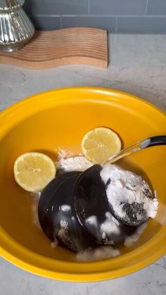 a yellow bowl filled with ice cream and two lemon wedges on top of it