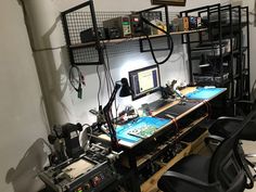 a desk with two monitors and several other electronic devices on top of it in a room