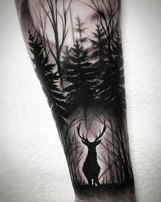 a man's arm with a black and white tattoo of a deer in the woods