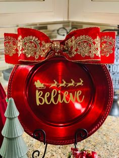 a red plate that says believe on it next to a christmas tree and other decorations