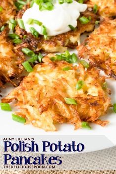 a white plate topped with potato cakes covered in sour cream and scalloped green onions