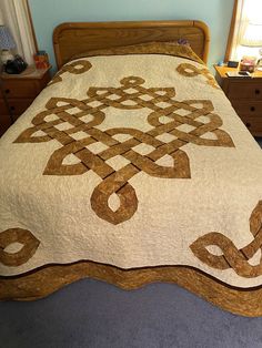 a bed with a white and brown quilt on it