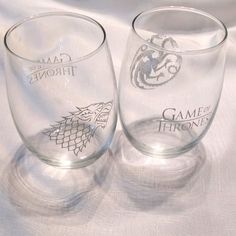 two game of thrones glasses sitting on top of a white cloth covered tablecloth