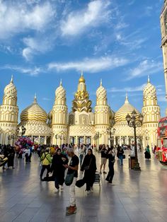 many people are walking around in front of a building with gold and white designs on it