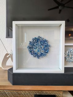 a white frame with blue beads in it on top of a table next to a television