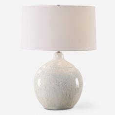 a white table lamp with a beige shade on the base and a white drum light