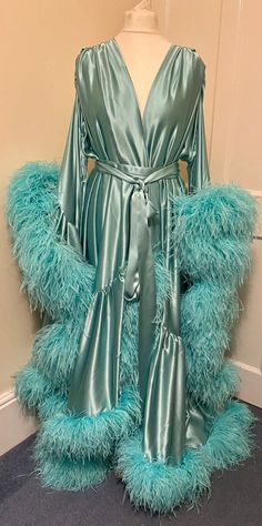 Beautiful chiffon dressing gown in Lagoon Breeze.  100% silk satin trimmed along the hem and the sleeve edges with luxurious ostrich feathers.  Fastens around the waist with a matching silk belt.  One size fits all due to the design, fullness and fabulousness of the robe.  Perfect for family gatherings, walking the dogs as well as taking out the rubbish. Please expect some feathers to shed - no one can look this fabulous without losing a few feathers. Long Sleeve Feather Robe For Parties, Satin Dresses With Feather Trim, Elegant Party Robe With Feather Trim, Elegant Satin Robe With Feathers, Elegant Feathered Evening Robe, Walking The Dogs, Feather Gown, Satin Dressing Gown, Feather Coat