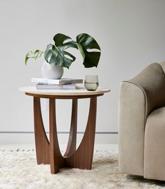 a table with a potted plant on it next to a couch and chair in a living room