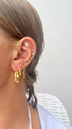 a close up of a person wearing ear piercings with gold colored metal items on their ears