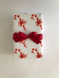 a white box with candy canes on it and a red bow around the top