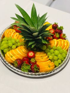 a platter filled with lots of fruit on top of a white tablecloth covered table