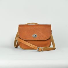 Our classic small cross body bag, crafted using rustic matte Tan leather. We love this small satchel style, and wanted to create a softer version, using the same supple, study, vegetable tanned leather which we use for our belts.  Measuring 19 x 15 x 5 cm, and with a strap adjustable between 128 and 137 cm, the vegetable tanning process beautifully preserves the organic past life of the material, creating a natural, characterful, finish, which will wear beautifully, taking on personality and charm with use.  Completed with a silver finish turnlock closure for accessibility and security, the minimal design aims to be an easy every day accessory. Always lovingly handmade in our London workshop.  Recently we have created a small run of accessories using the robust Italian vegetable tanned lea Everyday Leather Strap Saddle Shoulder Bag, Daily Use Crossbody Saddle Bag With Leather Strap, Everyday Saddle Shoulder Bag With Leather Strap, Classic Textured Leather Saddle Bag For Daily Use, Everyday Use Saddle Flap Bag With Adjustable Strap, Everyday Soft Leather Saddle Bag, Everyday Saddle Flap Bag With Adjustable Strap, Brown Saddle Bag With Leather Strap For Everyday, Textured Leather Satchel Flap Bag For Everyday Use