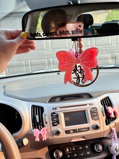 a car dashboard mirror with a pink butterfly hanging from it's side