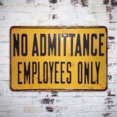 there is a yellow sign that says no admittance employees only on it against a white brick wall