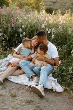 a family sitting on a blanket in front of flowers