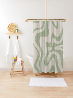 a green and white shower curtain with an abstract design on it, in a bathroom