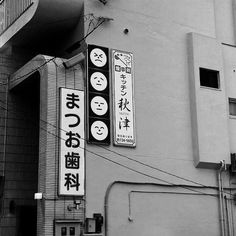 black and white photograph of signs on the side of a building in tokyo, japan