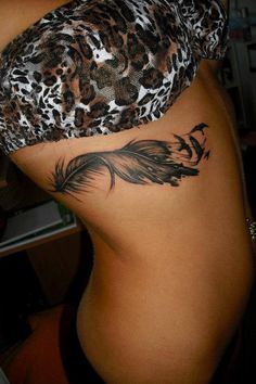 the back of a woman's stomach with a feather tattoo on her left side