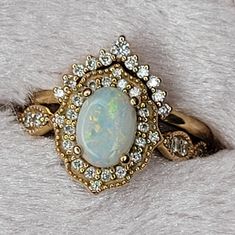 an opalite and diamond ring on top of a white furnishing surface