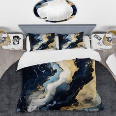 a bed with blue, gold and white marble pattern on the comforter is shown