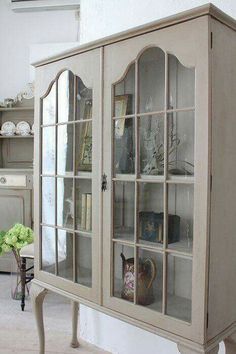 an old china cabinet with glass doors and shelves on the front, in a living room