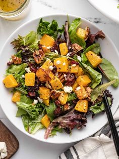 a salad with butternut squash and feta cheese on top in a white bowl