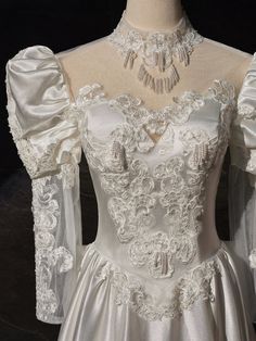 a white wedding dress with long sleeves and flowers on the bolery, is displayed