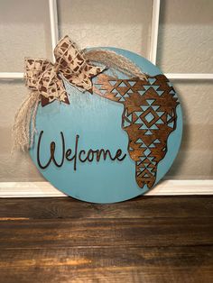 a welcome sign hanging on the front door with burlock and ribbon around it