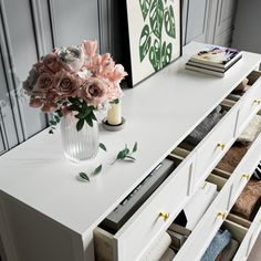 a white dresser with drawers and flowers on top