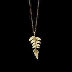 a gold necklace with two leaves hanging from it's sides on a black background