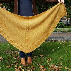 a woman holding up a yellow shawl in the grass