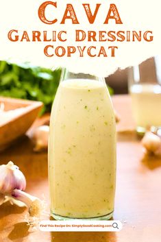 a glass bottle filled with liquid sitting on top of a wooden table next to garlic